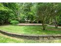 Well-maintained front yard with a stone retaining wall, manicured lawn, and mature trees at 3041 Shallowood Ln, Charlotte, NC 28277