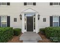 Well-lit condo entrance with a secure black door and trimmed green hedges at 4024 Town Center Rd, Harrisburg, NC 28075
