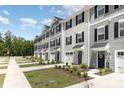 View of the townhomes with light gray siding, dark shutters, driveways, sidewalks and landscaping at 5690 Granbury Dr, Kannapolis, NC 28081
