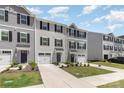View of gray siding townhomes with driveways, sidewalks, and a small grassy area in front at 5690 Granbury Dr, Kannapolis, NC 28081