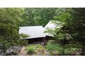 Exterior view of cabin showcasing its metal roof, log construction, and surrounded by lush trees at 720 Potneck Rd, Salisbury, NC 28147