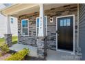 Welcoming front entrance with a black front door, gray stone facade, and Craftsman style columns at 9529 Cotswood Pl, Gastonia, NC 28056