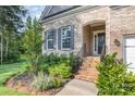Charming brick entrance with manicured garden, black iron railing, and inviting arched entryway at 11226 Dappled Light Trl, Charlotte, NC 28227