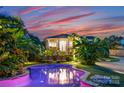 Inviting backyard pool reflecting the home's lights, surrounded by tropical foliage and lounge chairs at 117 N Central Ave, Belmont, NC 28012