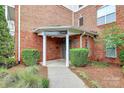 Building entrance featuring manicured shrubs, covered entryway, and brick facade at 14451 San Paolo Ln, Charlotte, NC 28277