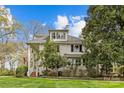 Charming two-story home with white siding, dormer windows, a welcoming front porch and lush landscaping at 1579 Queens W Rd, Charlotte, NC 28207