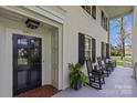 Inviting front porch featuring classic black rocking chairs, white columns and a charming entryway with sidelights at 1579 Queens W Rd, Charlotte, NC 28207