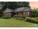 Charming brick home featuring a manicured front yard and lush landscaping, and mature trees in a desirable neighborhood at 43 Paddington Sw Dr, Concord, NC 28025