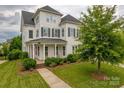 Well-maintained two story home with covered porch, American flag, and established trees on a landscaped lawn at 5256 Meadowcroft Way, Fort Mill, SC 29708