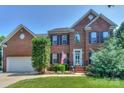 Charming two-story brick home with manicured lawn, American flag, and attached two-car garage at 6873 Lakecrest Ct, Denver, NC 28037