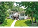 Exterior view of waterfront home featuring a two-story deck, landscaped lawn, and mature trees at 7010 Coventry Ct, Tega Cay, SC 29708