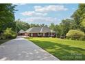 Elegant brick home featuring a detached garage, expansive lawn, and meticulously maintained landscaping at 7612 Maple Bluff Ln, Concord, NC 28025