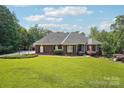 Charming brick home showcasing a beautiful lawn, mature shrubs, and classic architectural details at 7612 Maple Bluff Ln, Concord, NC 28025