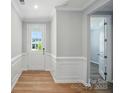 Inviting entryway with wood floors, white wainscoting, neutral paint, and a view into an adjacent room at 9846 Quercus Ln, Huntersville, NC 28078