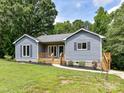 Charming blue home with a lovely wooden porch and well-manicured lawn, set against a backdrop of lush trees at 1117 Hidden Brook Ln, Clover, SC 29710
