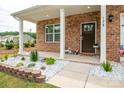 Cozy front porch with brickwork, decorative flowerbeds, and a welcoming entrance with excellent curb appeal at 128 Hickory Ridge Dr, Locust, NC 28097