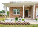 Charming front porch featuring brick accents, decorative flowerbeds, and a welcoming entrance with curb appeal at 128 Hickory Ridge Dr, Locust, NC 28097