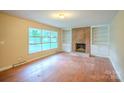 Cozy living room showcasing hardwood floors, a brick fireplace with built-in shelves and ample natural light at 1332 Midwood Dr, Gastonia, NC 28052