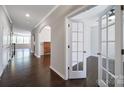 Elegant hallway features dark hardwood floors, arched doorways, and access to a bright office with glass doors at 1604 Trentwood Dr, Fort Mill, SC 29715