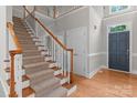 Elegant carpeted staircase with wood railing leads to the upper level; front door shown at 165 Futrell Lndg, New London, NC 28127