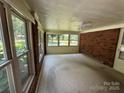 Bright sunroom with brick walls, large windows offering scenic views, and carpeted floors at 34393 Springdale Dr, New London, NC 28127