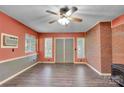 Cozy living room with wood-look floors, brick accent wall, ceiling fan, and natural light at 37156 Southside Rd, Albemarle, NC 28001