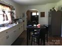 View of kitchen with white cabinets, stainless refrigerator, and dining table at 448 Belk St, Lancaster, SC 29720