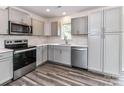 A well-lit kitchen boasts stainless steel appliances, gray cabinetry, and stylish backsplash and flooring at 5306 Lee Massey Rd, Waxhaw, NC 28173