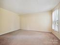 Bright, carpeted bedroom featuring a neutral color scheme and a window with sheer curtains for soft, natural light at 7639 Winterset Dr, Charlotte, NC 28270
