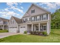 Charming two-story home with gray siding, black shutters, a three-car garage, and a well-manicured lawn at 808 Dogwood Creek Ln, Indian Trail, NC 28079
