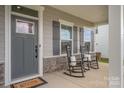 Inviting front porch with gray door, gray shutters, and classic black rocking chairs for relaxed outdoor living at 808 Dogwood Creek Ln, Indian Trail, NC 28079