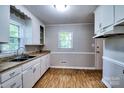 Bright kitchen featuring wood-look flooring, white cabinets, and ample natural light from two windows at 828 Williams St, Gastonia, NC 28052