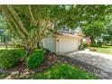 Side view of home with a two-car garage, landscaped yard and mature tree at 8701 Appaloosa Way Ln, Charlotte, NC 28216