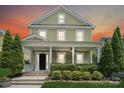 Charming two-story home with a welcoming front porch, manicured landscaping, and lush greenery at 12525 Druids Glen Dr, Pineville, NC 28134
