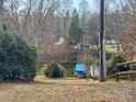 Lush backyard with a boat covered with a blue tarp, surrounded by mature trees and greenery at 3433 Spinner Ct, Sherrills Ford, NC 28673