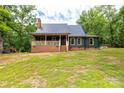 Inviting home featuring a covered front porch with brick foundation, metal roof, and verdant lawn at 3547 Willowood Pond Dr, Rock Hill, SC 29730
