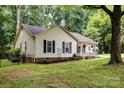 Side view of a cozy home featuring black shutters, landscaping, and a well-maintained lawn and porch at 713 Hickory Hill Ct, Gastonia, NC 28054