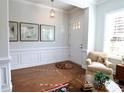 Welcoming foyer featuring hardwood floors, wainscoting, a cozy chair, and decorative artwork at 914 Greenbridge Dr, Matthews, NC 28105