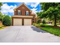 Charming brick home featuring a two-car garage, lush landscaping, and a welcoming driveway at 10418 Pullengreen Dr, Charlotte, NC 28277