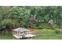 Waterfront home featuring a covered dock with a boat lift, lush landscaping, and lake views at 138 Ardmore Pl, Mooresville, NC 28117
