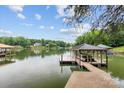 Waterfront dock with covered boat slip, featuring multiple boats and a serene lake backdrop under a partly cloudy sky at 138 Ardmore Pl, Mooresville, NC 28117