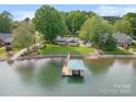 Aerial view of lakefront home with a boat dock, lush lawn, and mature trees at 173 Riverwood Rd, Mooresville, NC 28117