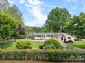 Charming single-story home featuring mature trees, lush lawn, and a welcoming front entrance at 173 Riverwood Rd, Mooresville, NC 28117