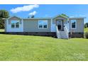 Manufactured home with light beige siding, white trim, a brick foundation and a manicured lawn at 4713 White Store Rd, Wingate, NC 28174