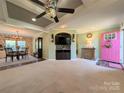 Open-concept living room showcasing a decorative ceiling fan, a pink front door, and neutral carpet at 4713 White Store Rd, Wingate, NC 28174