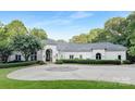 Elegant white home with a circular driveway and lush landscaping at 7912 Baltusrol Ln, Charlotte, NC 28210