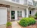 Inviting front porch featuring a bench, manicured landscaping, and stone accents on the townhome at 13909 Singleleaf Ln, Charlotte, NC 28278