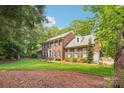 Stately brick home features manicured lawn, complemented by a beautiful landscape and mature trees at 1545 Chadmore Nw Ln, Concord, NC 28027