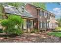 Side angle of a lovely two-story brick home featuring blue shutters and well-maintained landscaping at 1545 Chadmore Nw Ln, Concord, NC 28027