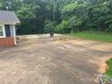 The backyard features a spacious concrete pad, surrounded by lush greenery and mature trees at 2116 Dana Pl, Shelby, NC 28152